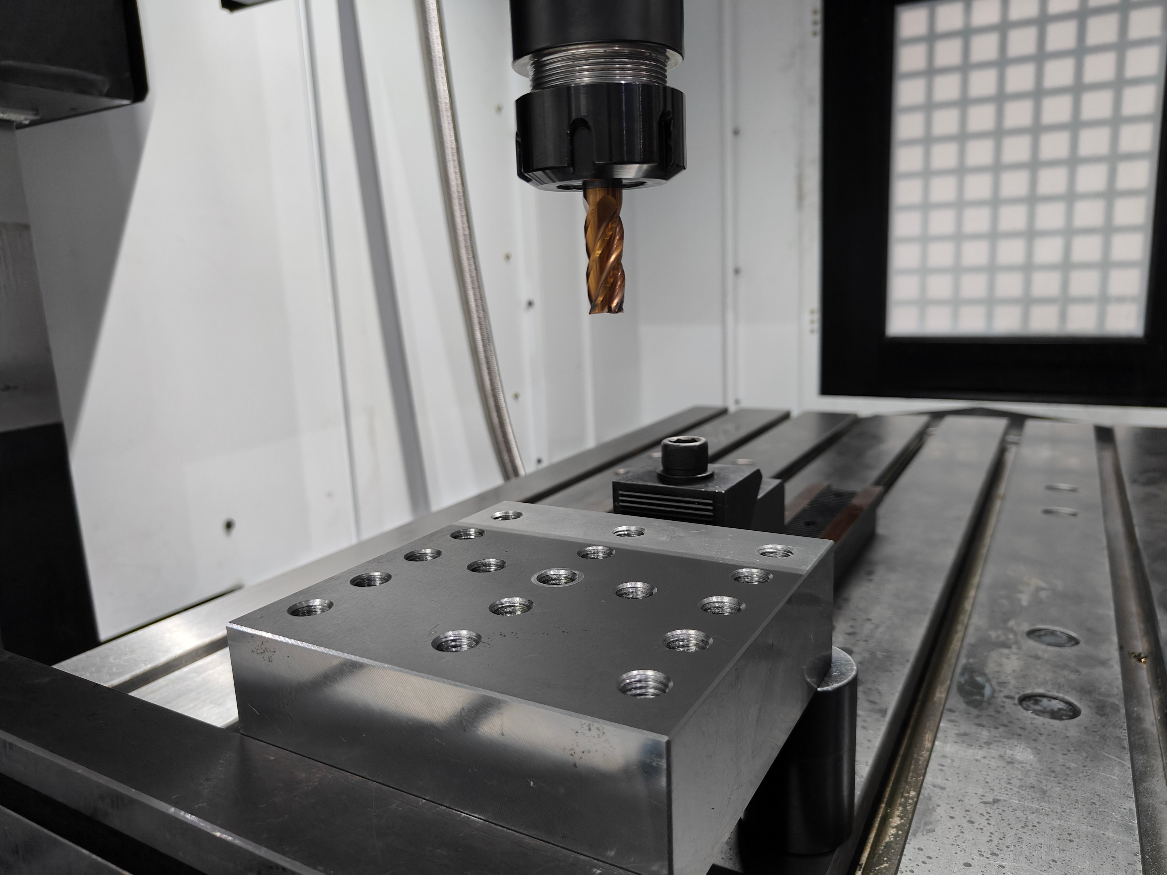 End mill held in a CNC spindle above a steel workpiece during roughing