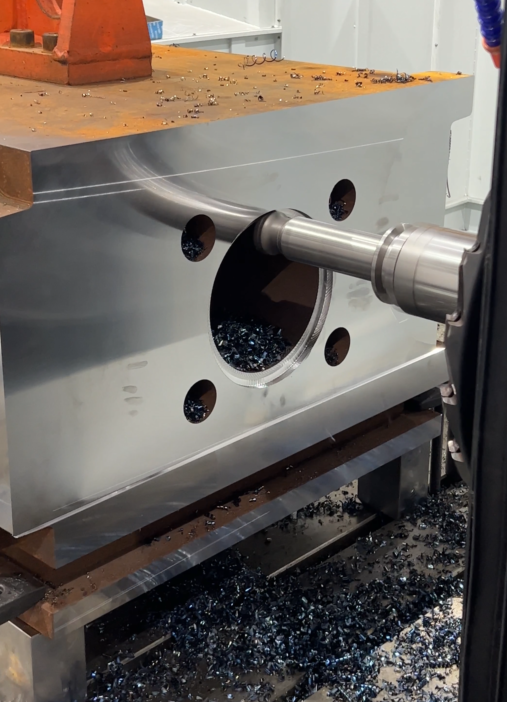 Machining a deep mold cavity with chips visible around the opening